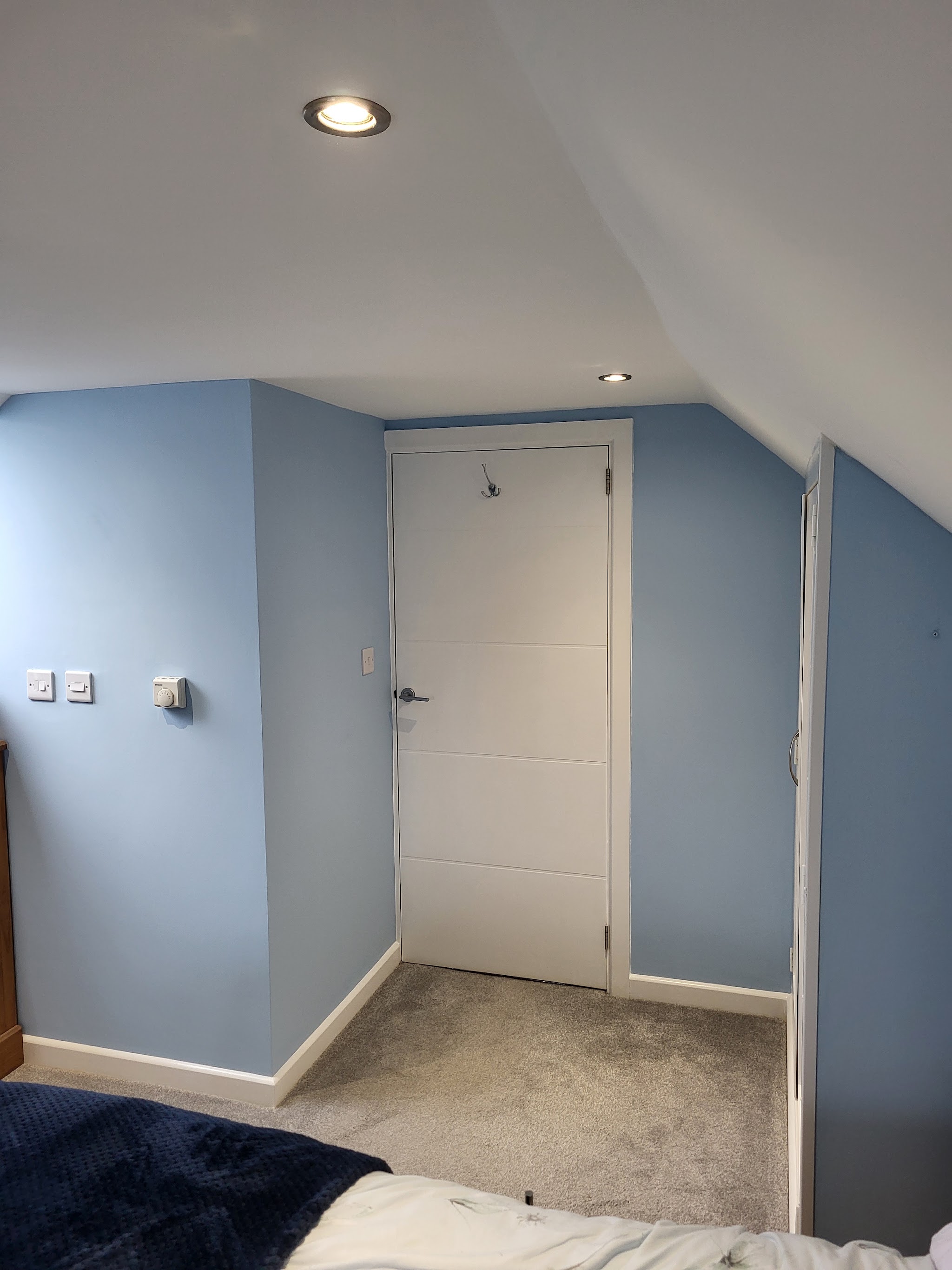 Bedroom decorated in pale blue with crisp white door and skirting